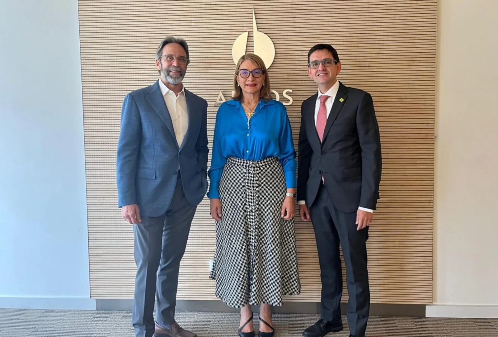 Tres representantes posan de pie ante el mural con el logo Argos tras el anuncio de la alianza