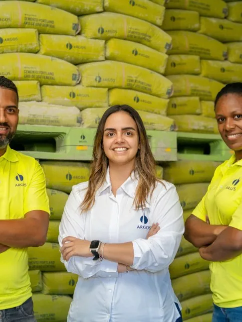 Tres colaboradores de Argos Dominicana frente a estibas de cemento en planta